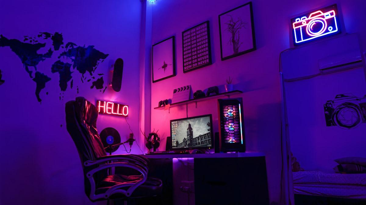 A neon-lit gaming corner with a PC, gaming chair and wall art
